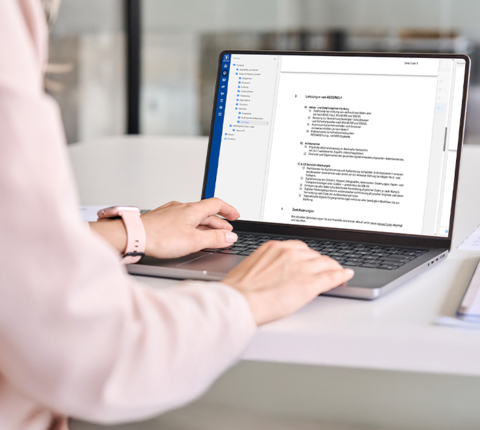 Hände bearbeiten Dokumente digital am Laptop in der REISSWOLF dok. suite.