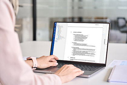 Mitarbeiterin bearbeitet digitalisierte Dokumente am Laptop