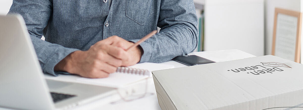 Arbeiten im Home Office Nahaufnahme eines Schreibtisches im Home Office, mit Laptop, Schreibutensilien und der Dokumenten. Box. von REISSWOLF